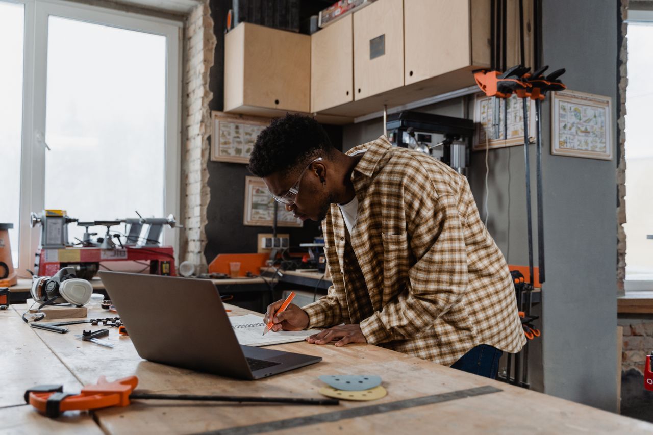 A small business owner working at a laptop in a bright workshop.