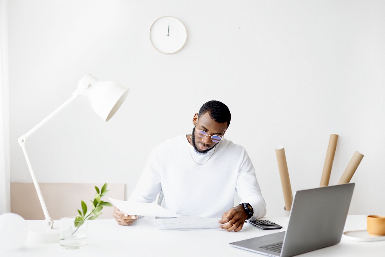 An accountant reviewing financial documents at a tidy desk in a bright office.