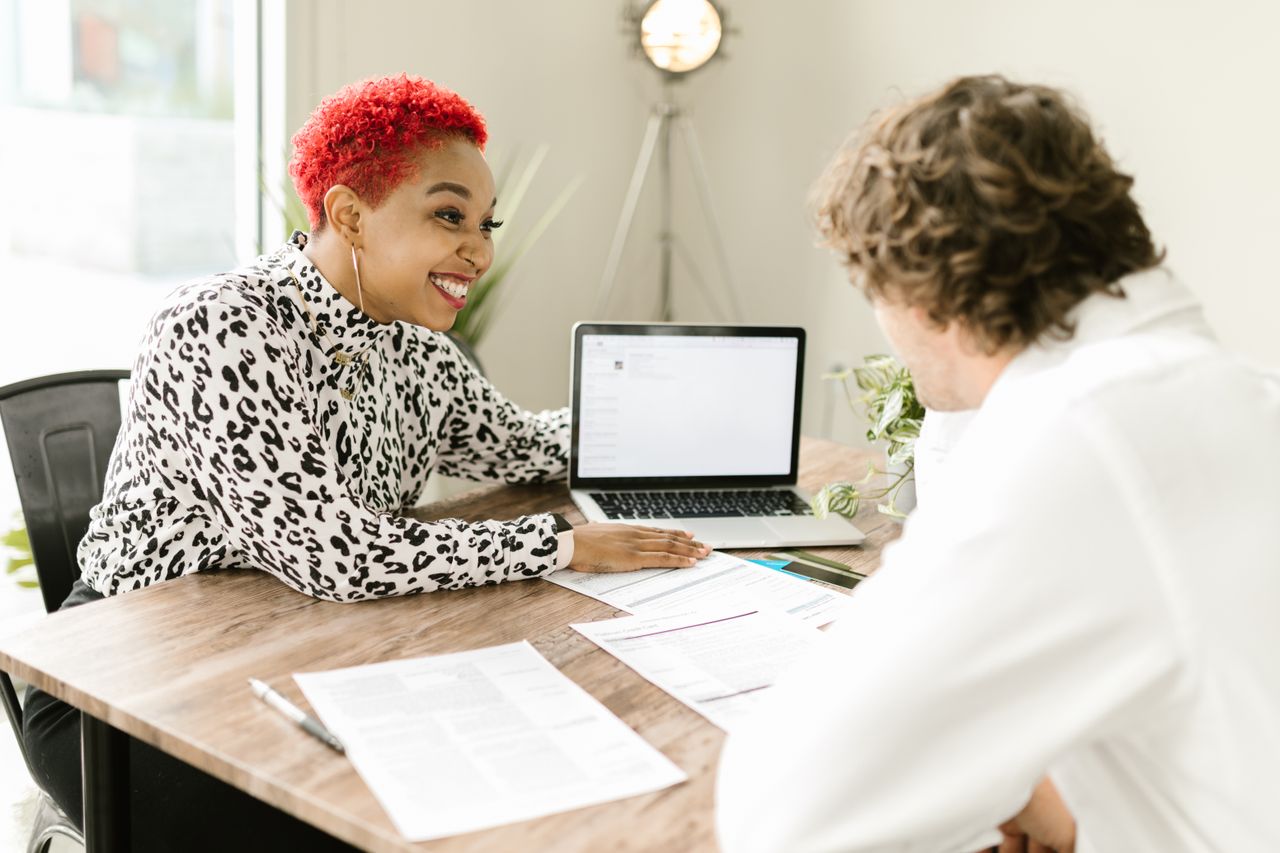 A coach talking with a client across a desk in a bright modern office.